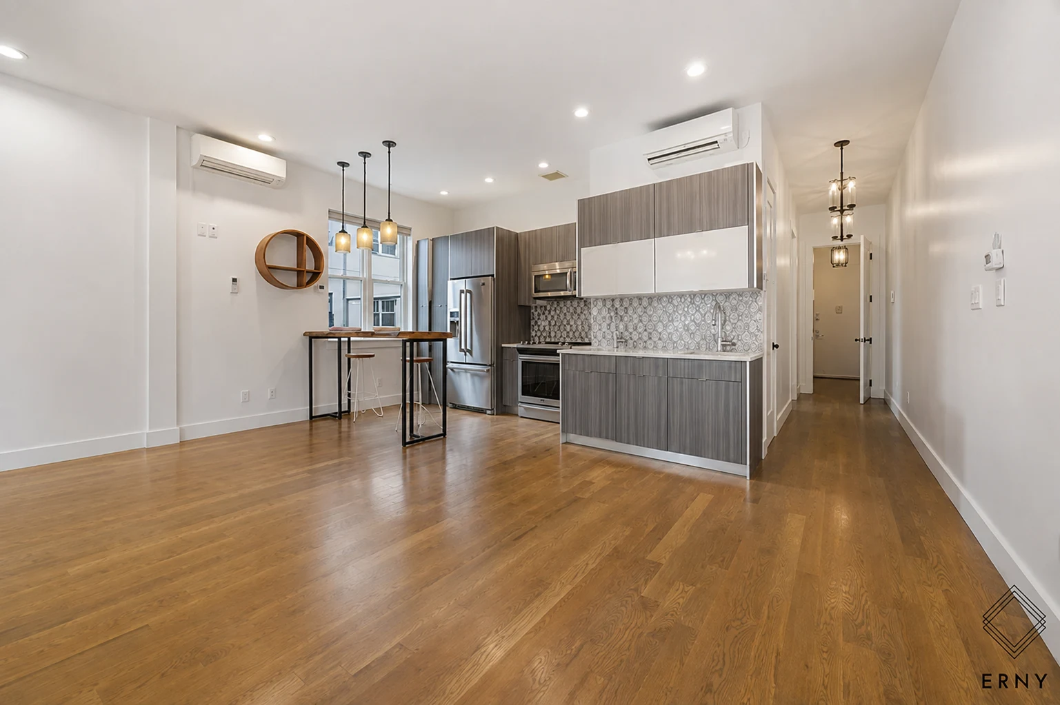 Open kitchen and living area with wood flooring, white walls and trim