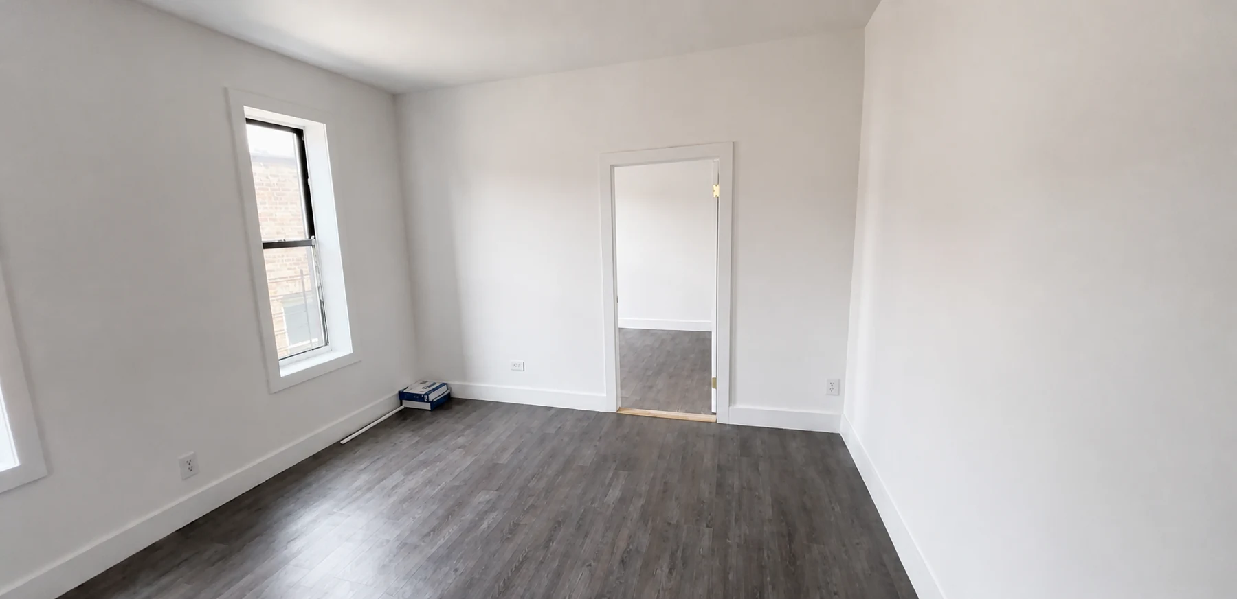 Finished room with dark laminate flooring, white walls and a white door